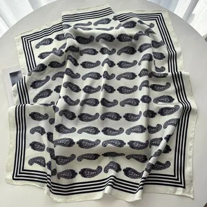 Detail of off-white paisley silk scarf showing soft fabric folds and navy border