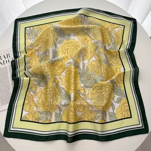 Détail macro du foulard carré en soie avec fleurs jaunes et bordures vert foncé