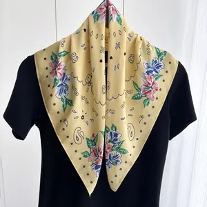 Close-up of yellow silk scarf with vibrant paisley flower patterns and elegant fabric texture