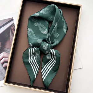 Close-up of silk scarf with white paisley pattern in an elegant gold-trimmed gift box