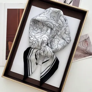 Détail d'un foulard en soie noir et blanc à motif floral élégant dans un plateau doré