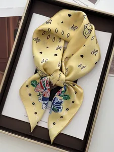 Detail of yellow silk scarf featuring paisley floral patterns in a luxury display gift box