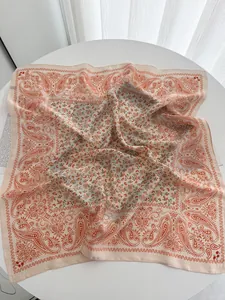 Close-up of floral silk square scarf with orange paisley borders and peach background