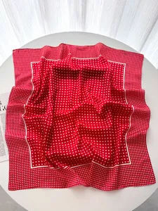 Close-up of a large red silk scarf with white polka dots and elegant satin finish