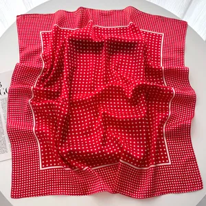 Detail shot of a red and white polka dot silk scarf draped over a white surface