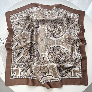 Detailed close-up of a large square silk scarf with classic brown paisley patterns