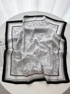 Détail d'un foulard carré en soie de 70cm avec imprimés floraux noirs et bordures noires