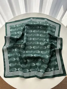 Detail view of dark green silk square scarf with classic white paisley pattern