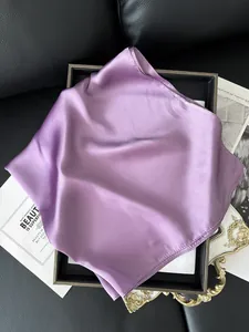 Gros plan d'un foulard carré en satin violet montrant la texture soyeuse et lisse