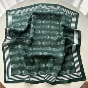 Detailed close-up of dark green paisley silk scarf with white border on a round table