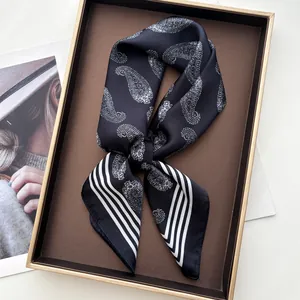 Close-up of black silk scarf with white paisley pattern and stripes in a gift box