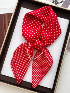 Detailed view of red and white polka dot silk scarf tied in a neat bow inside a gift box
