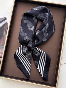 Detail of silk scarf with white paisley pattern and striped edge on a display tray