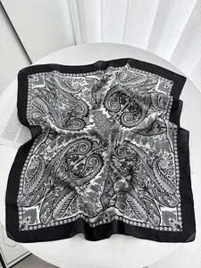 Detail of vintage cashew paisley print silk scarf with wide black border flat on white table