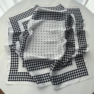 Detail of black and white silk scarf with houndstooth edge and satin texture on a table
