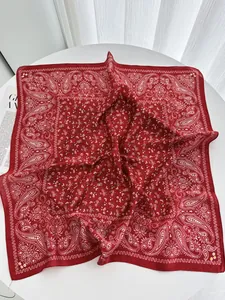Detail of red floral paisley silk scarf draped elegantly on a white table background