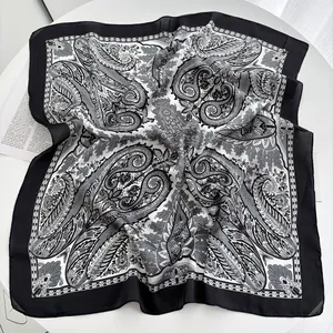 Detail shot of square silk scarf with black and white paisley patterns on table