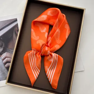 Detail of vibrant orange silk scarf with paisley patterns and elegant stripes