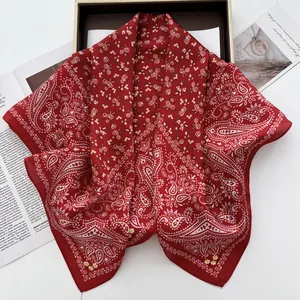 Detail of dark red paisley floral silk square scarf elegantly placed on a gift box