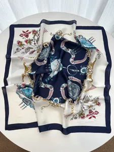 Detail of silk-like square scarf featuring elegant gold chain and floral prints