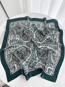Detail of a vintage dark green paisley print silk square scarf on a white table