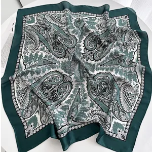 Detailed view of square silk scarf with green paisley patterns and rolled hem edge