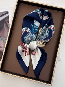 Detail of silk-like square scarf with belt chain print on a brown display tray