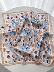 Dettaglio di un foulard in seta a fiori con bordo in raso rosa su tavolo bianco