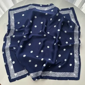 Detailed macro view of navy blue silk square scarf with classic white polka dot patterns