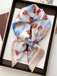 Vista dettagliata del foulard in seta con stampa a tulipani, piegato in una confezione regalo dorata
