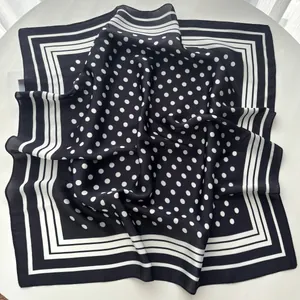 Detailed view of square silk scarf with classic white polka dots on black background
