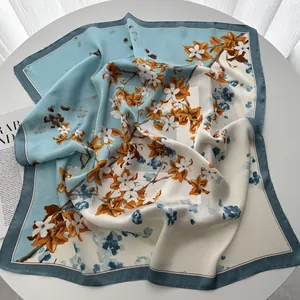 Détail d'un carré de soie avec fleurs orange sur une texture de satin très douce