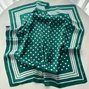 Close-up of deep green silk square scarf with white polka dots and striped geometric border