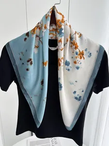 Détail d'un foulard en soie élégant avec motifs floraux bleu et orange sur noir