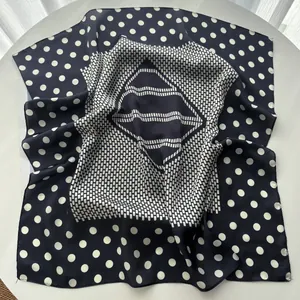 Detail of silk-like navy blue square scarf with white polka dots and geometric patterns