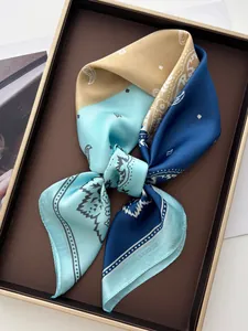 Détail d'un foulard carré en satin de soie avec imprimé paisley et pois bleu et jaune