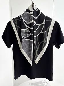 Close-up of geometric grid pattern silk scarf styled on a minimalist black shirt