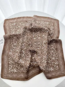 Detailed macro view of a brown silk square scarf with white paisley and floral patterns