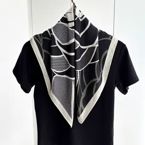 Detail of square silk scarf showing geometric grid patterns and abstract leaf design