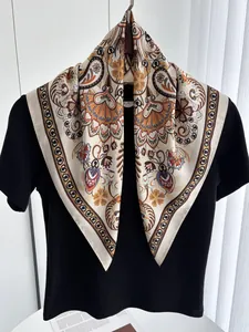 Detailed macro view of orange and beige paisley floral silk scarf on a black shirt