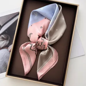 Gros plan d'un foulard en satin imprimé cachemire plié dans une boîte cadeau