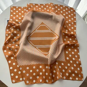 Detailed close-up of vintage orange silk square scarf with white polka dots and geometric pattern