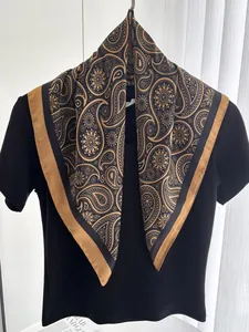 Detail eines luxuriösen Seidenschals mit schwarz-goldenen Paisleymustern auf einem T-Shirt