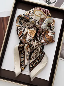 Macro detail of silk square scarf with vintage paisley pattern on a decorative tray