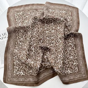 Brown silk-like square scarf with white paisley pattern on a white round table