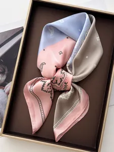 Détail d'un carré de soie satiné avec motifs paisley bleu et rose noué en ruban chic