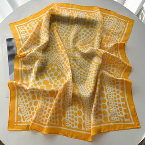 Detailed view of yellow and white polka dot silk scarf showing silky texture and hem