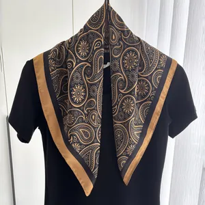 Detail eines Seidenschals mit goldenen Paisleymustern und luxuriösem Satin-Randbesatz