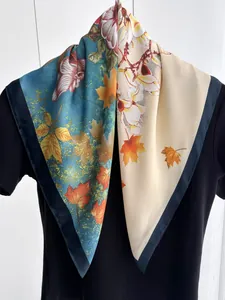 Détail d'un élégant foulard carré en satin avec motifs floraux bleu paon et feuilles d'érable