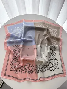 Détail d'un foulard carré en satin avec motifs paisley et design patchwork bicolore